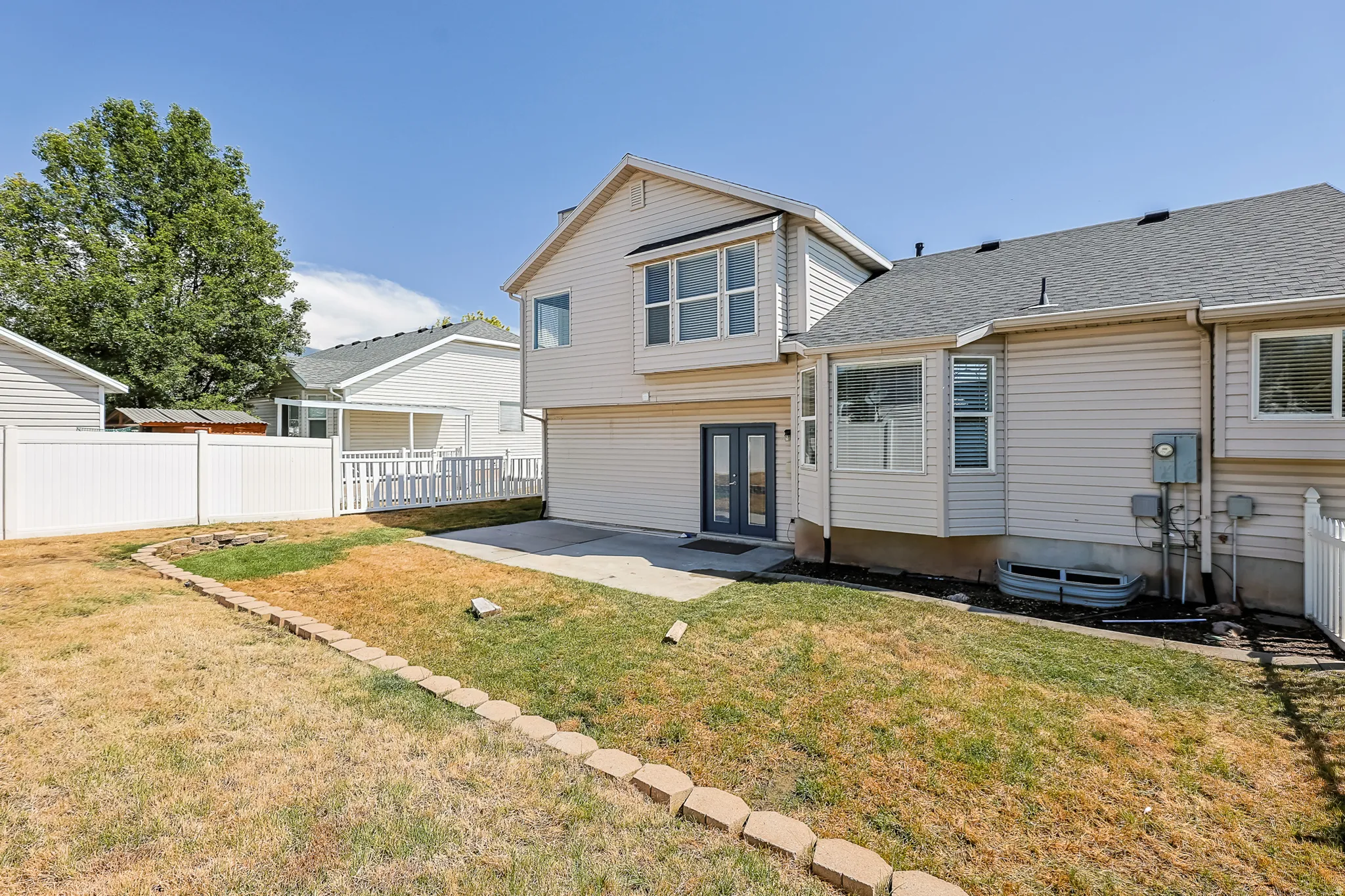 Exterior siding home featuring a concrete patio, double glass panel doors, and bay windows