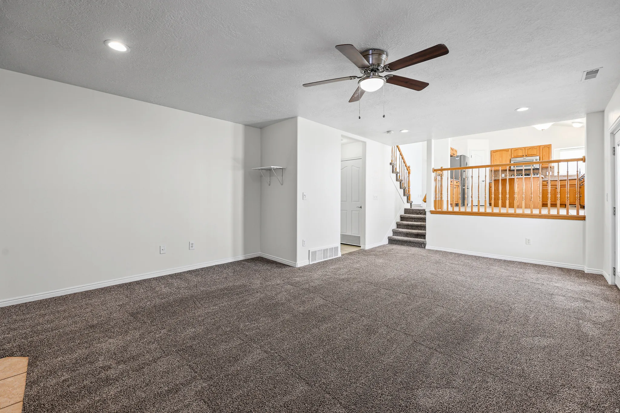 Expansive living area with neutral carpeting and recessed lighting