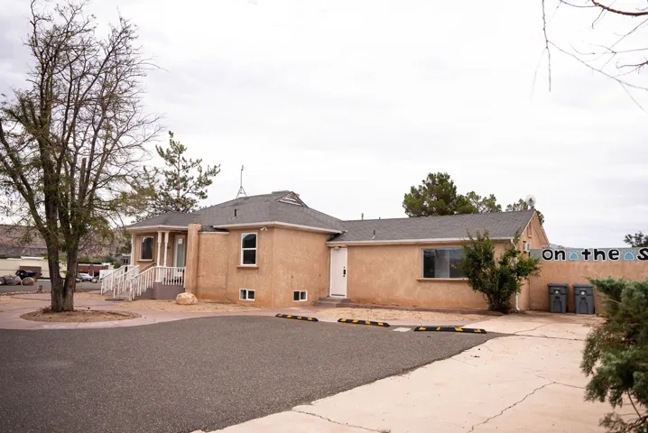 Stucco exterior with a covered entry, white porch railing, and an asphalt shingle roof