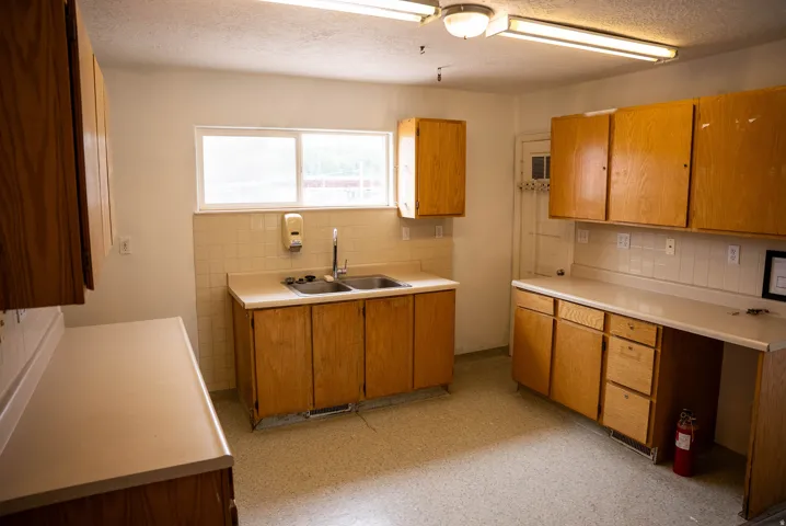 Spacious kitchen area featuring extensive wood-finish cabinetry, ample countertop space, a double basin sink, and a large window