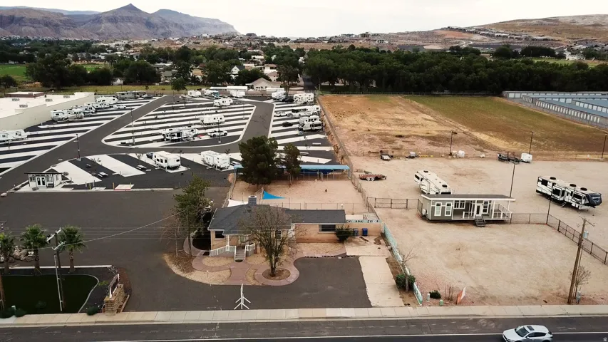 Aerial perspective showcasing a mixed-use commercial property with paved RV parking spaces, a single-story building with a dark roof, and an expansive open lot