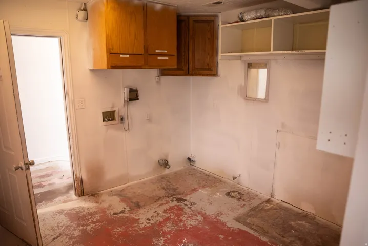 Utility area featuring upper cabinetry, open shelving, and plumbing hookups