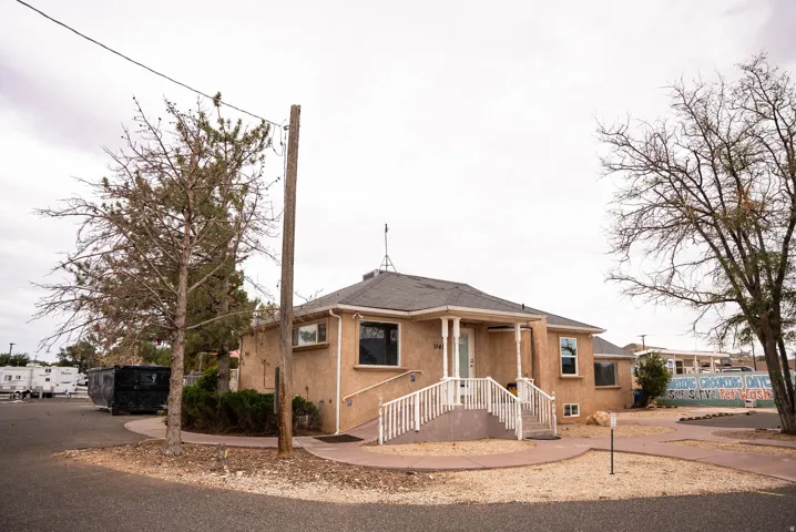 Stucco exterior with a covered entry porch, white railings, and a front walk leading to the entrance