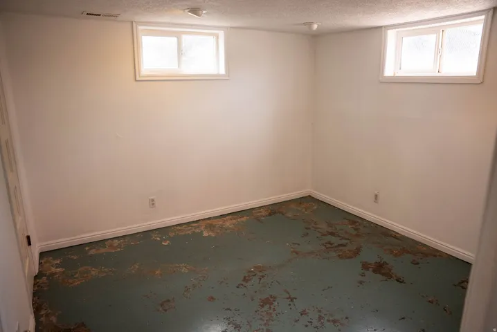 Room featuring two windows, white walls, white baseboards, and a textured ceiling
