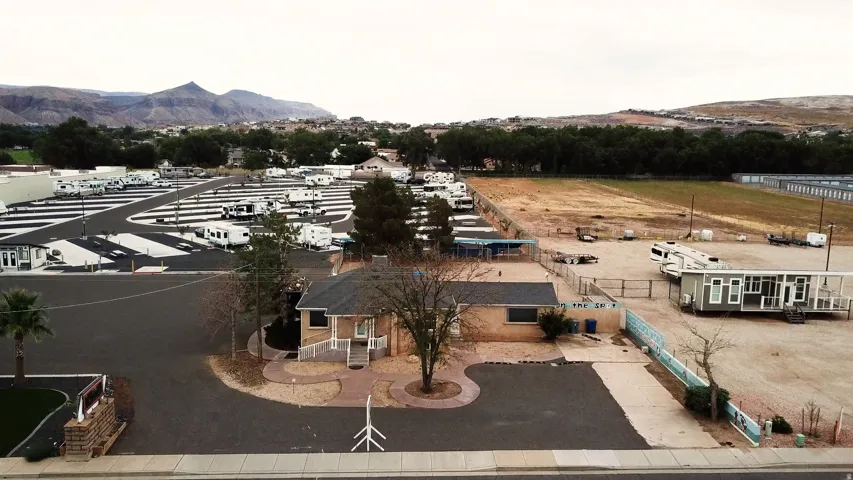 Expansive parcel featuring a central building with a gabled roof and surrounding paved areas