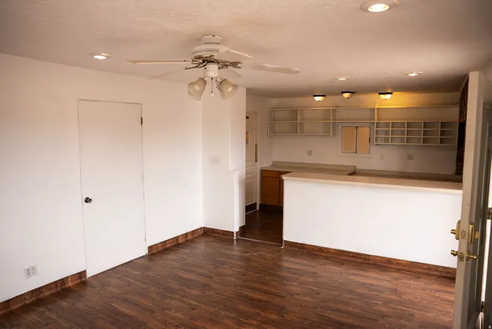 Spacious open-concept area featuring wood-finish flooring, a ceiling fan with integrated lighting, and recessed ceiling lights