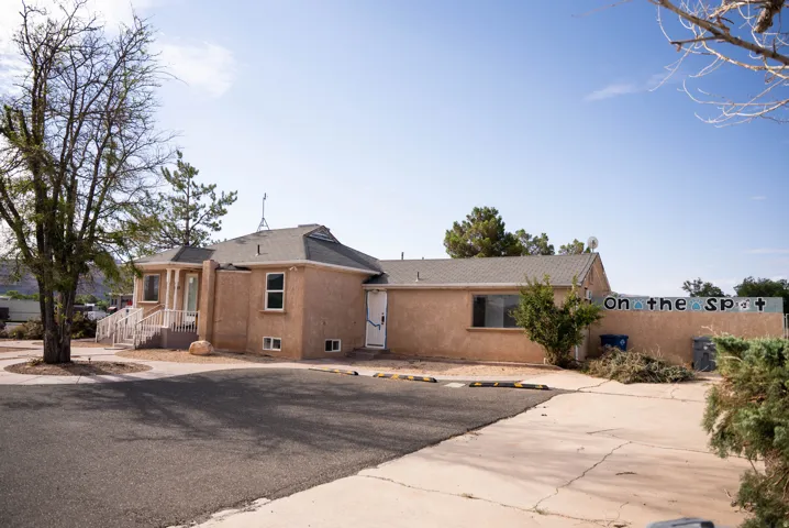 Stucco exterior building with a gray shingle roof and multiple window styles