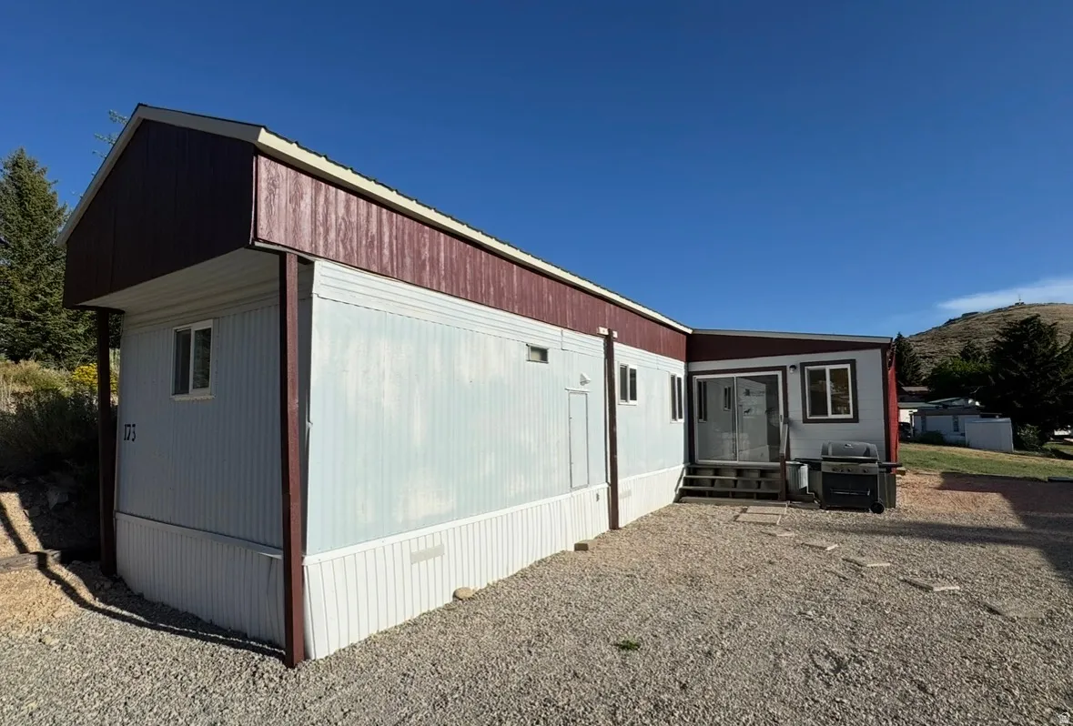 Light blue siding exterior with dark red trim and gable roofline