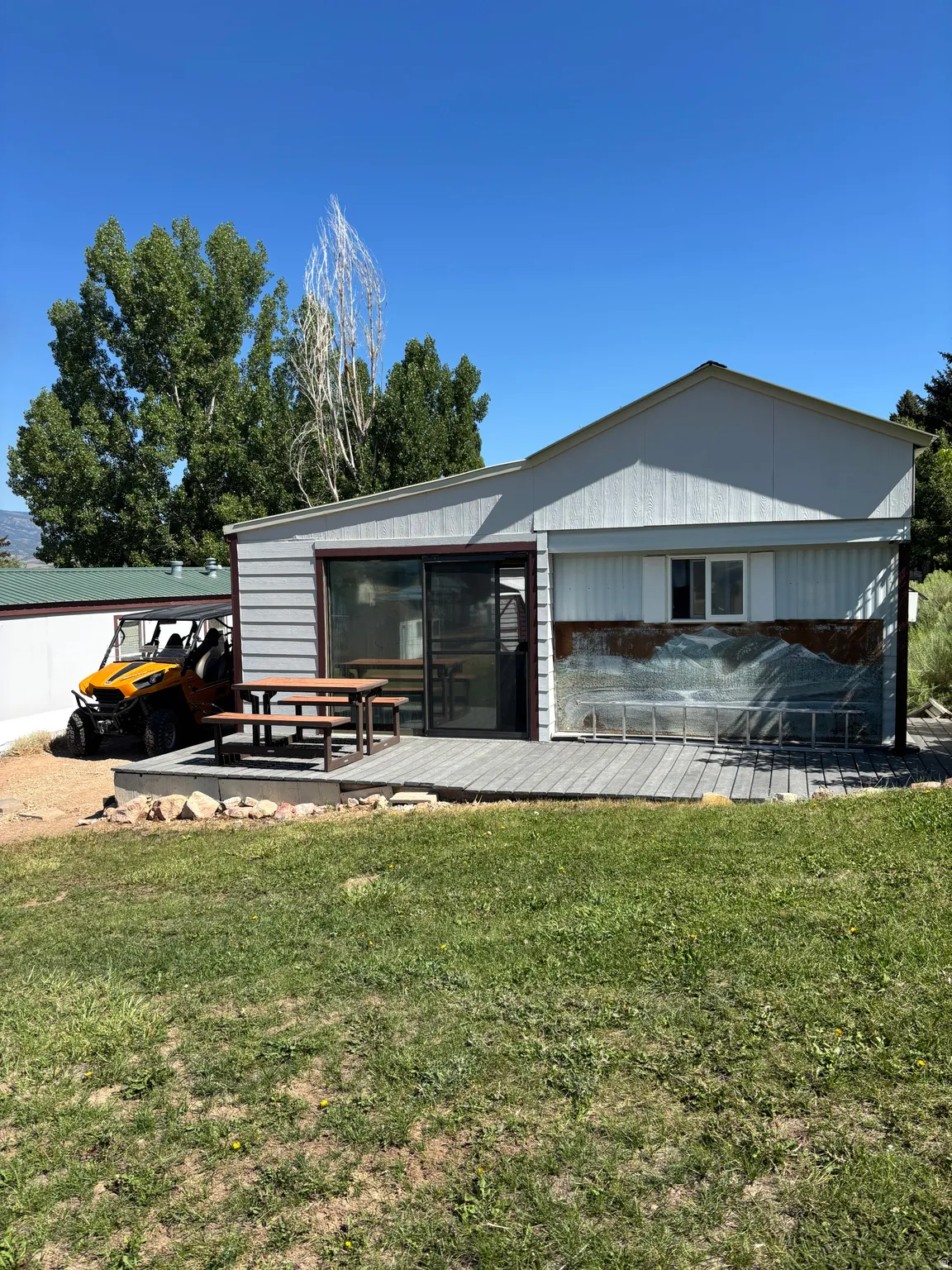 Exterior featuring a raised deck with composite decking, sliding glass door, and white siding