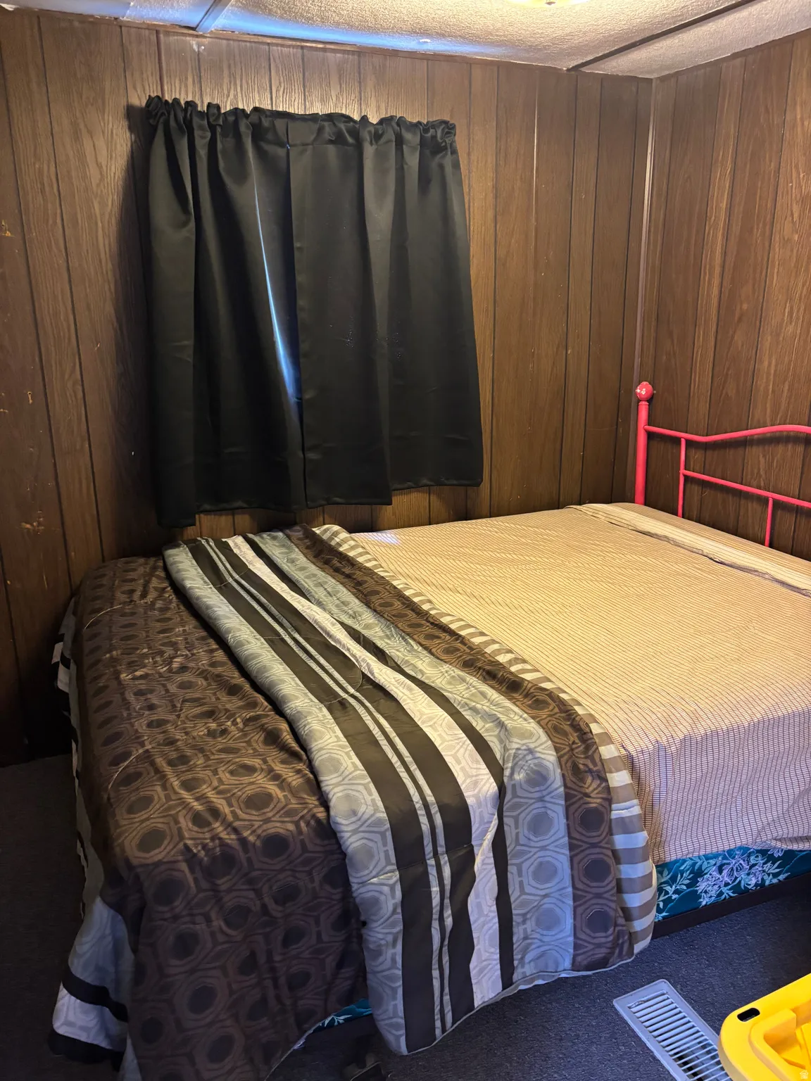 Room featuring wood-paneled walls and a window with dark curtains