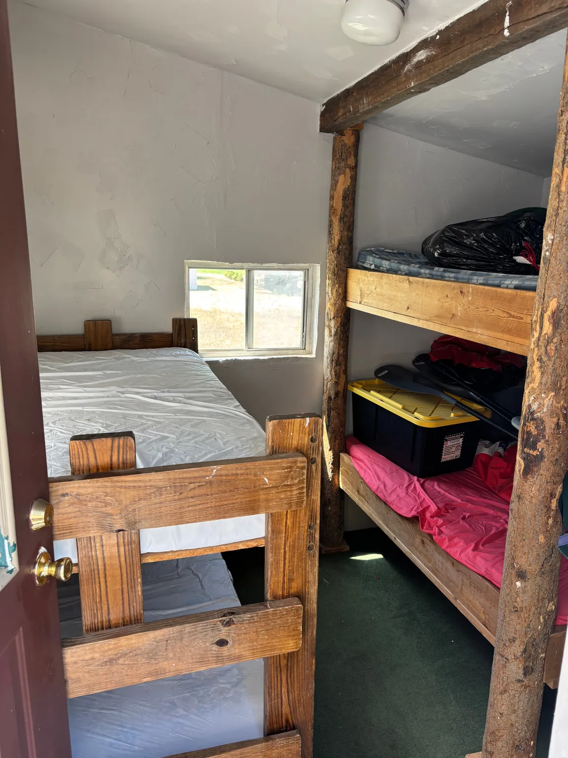 Room featuring built-in bunk beds with natural wood frames, a single-pane horizontal window, and white textured walls