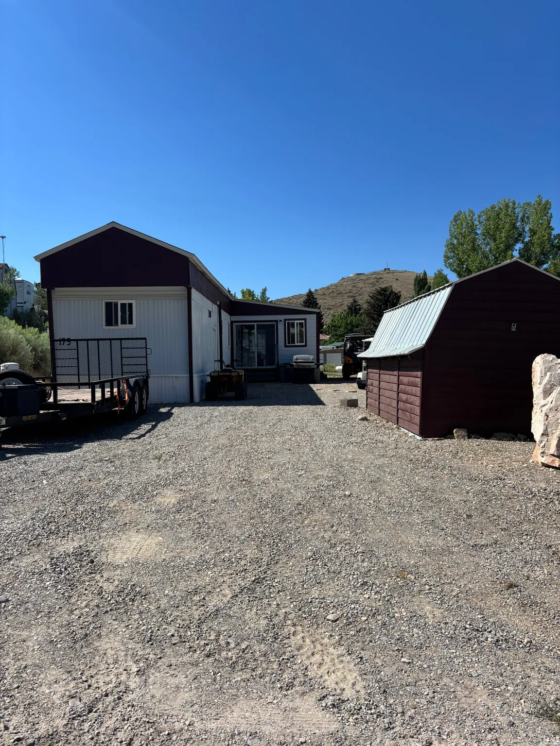 Gravel driveway leading to a residence with white siding and a dark roof