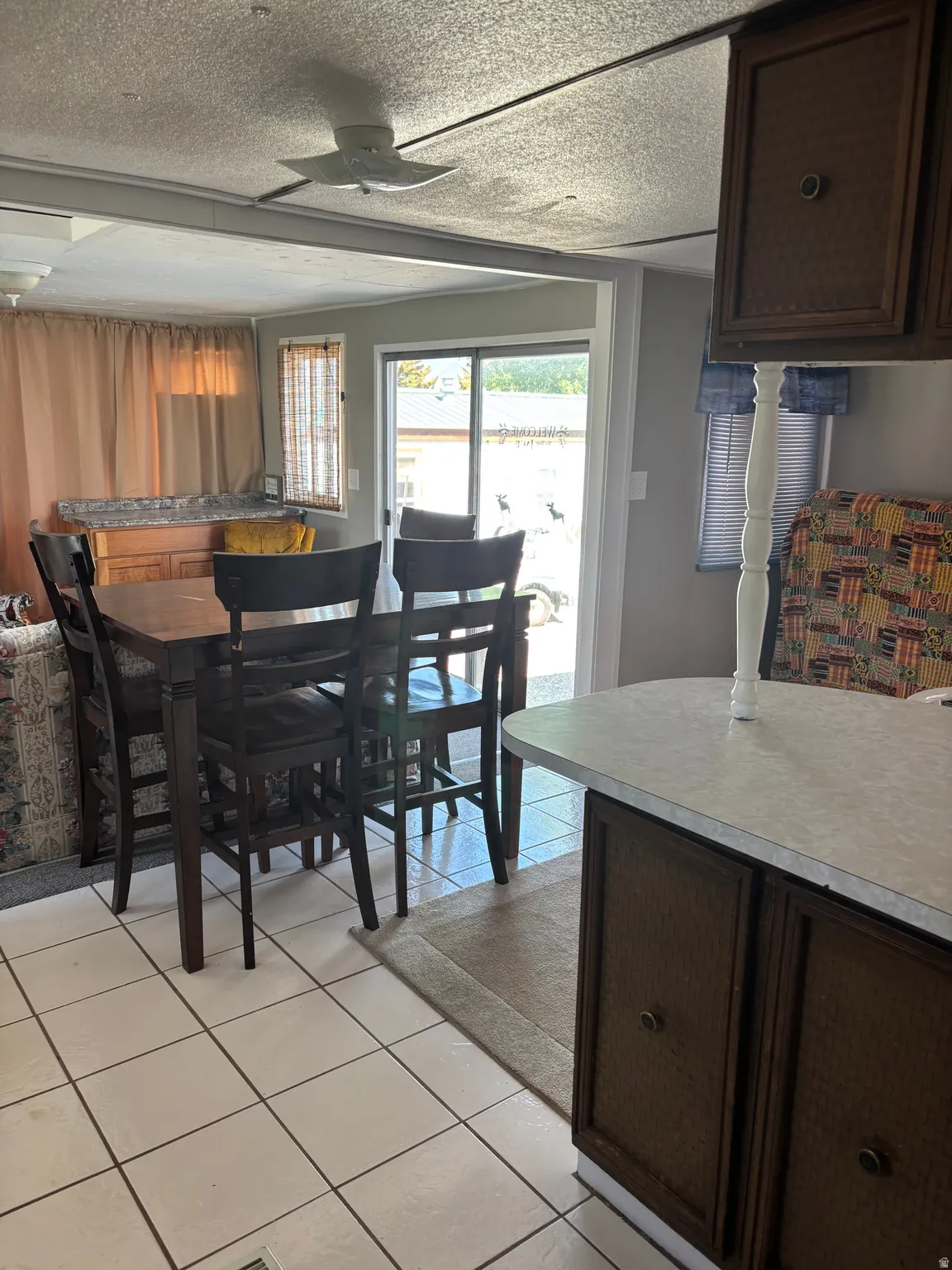 Open concept dining area with white tile flooring and a ceiling fan