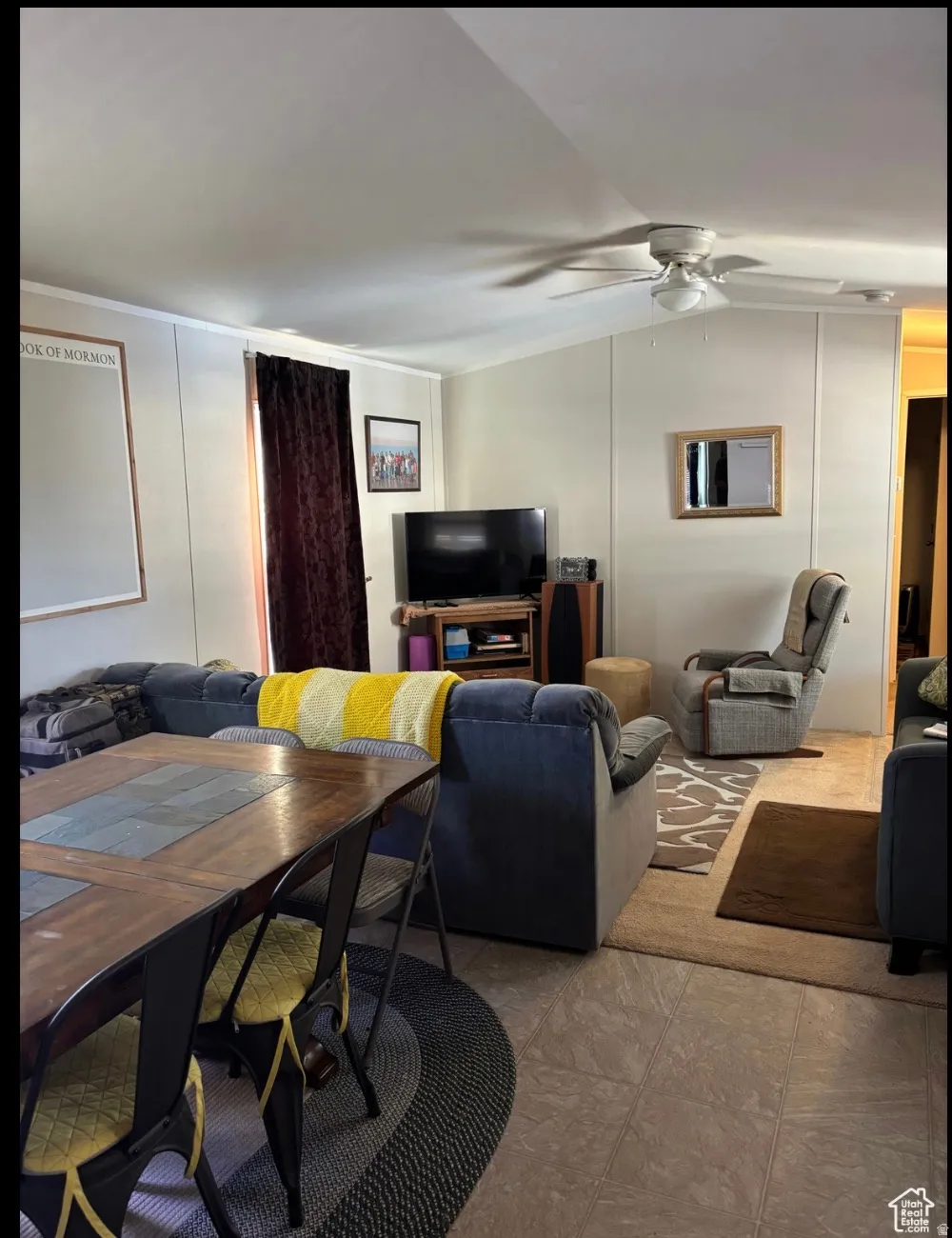 Open-concept living space featuring neutral tone flooring, a ceiling fan with integrated lighting, and vertical wall paneling