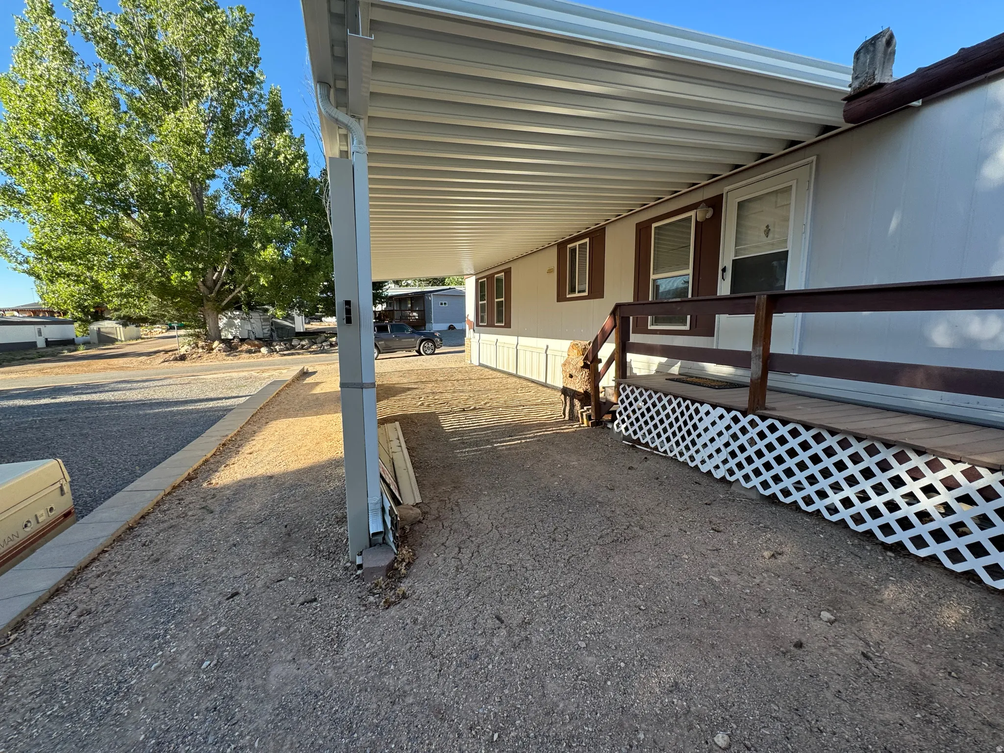 Covered entrance with a wood-finish ramp and lattice skirting, featuring white siding and brown trim