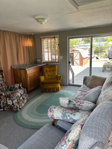 Interior living space featuring light gray walls, carpet flooring, a built-in counter with wood cabinetry, and a sliding glass door providing exterior access