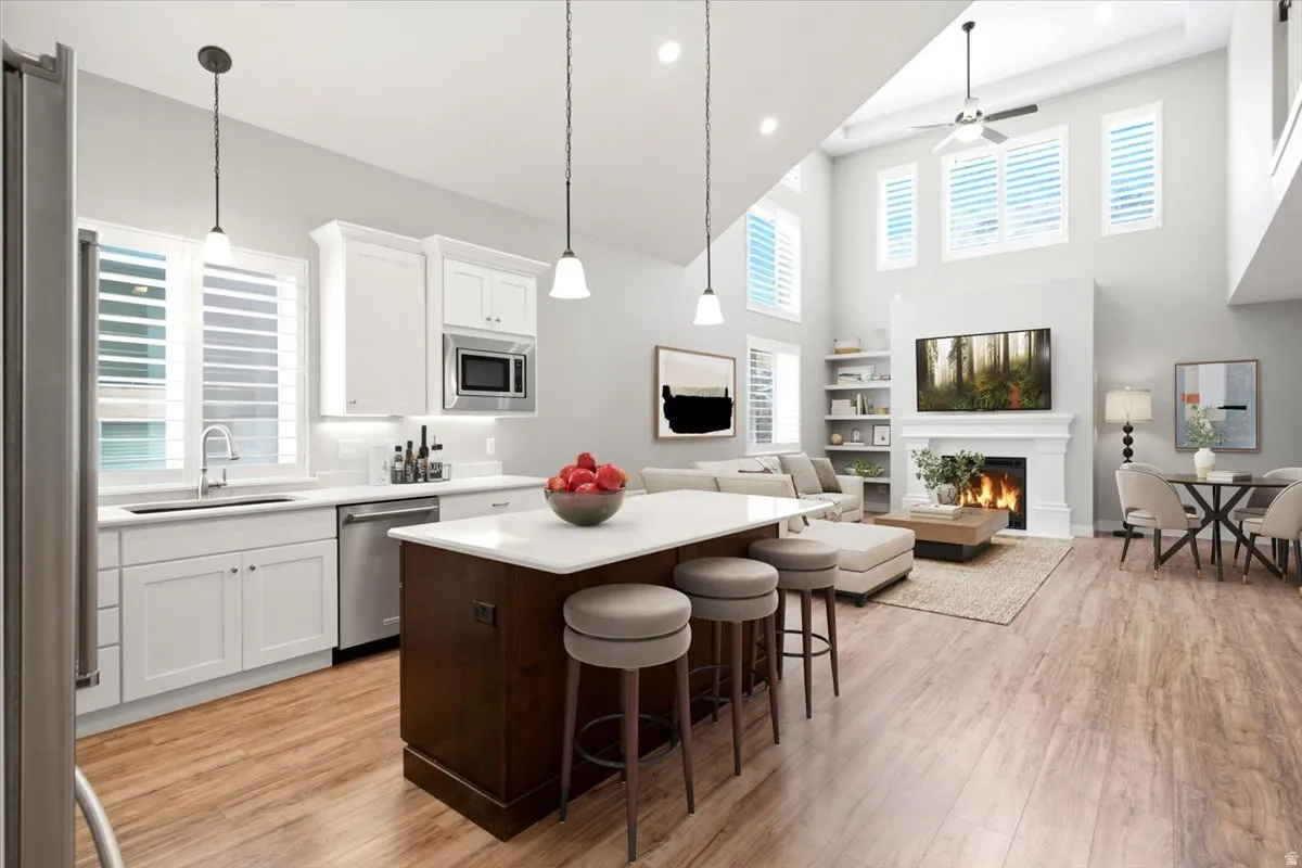 Open-concept living space featuring a two-story ceiling, wood-finish flooring, and a fireplace with a mantel
