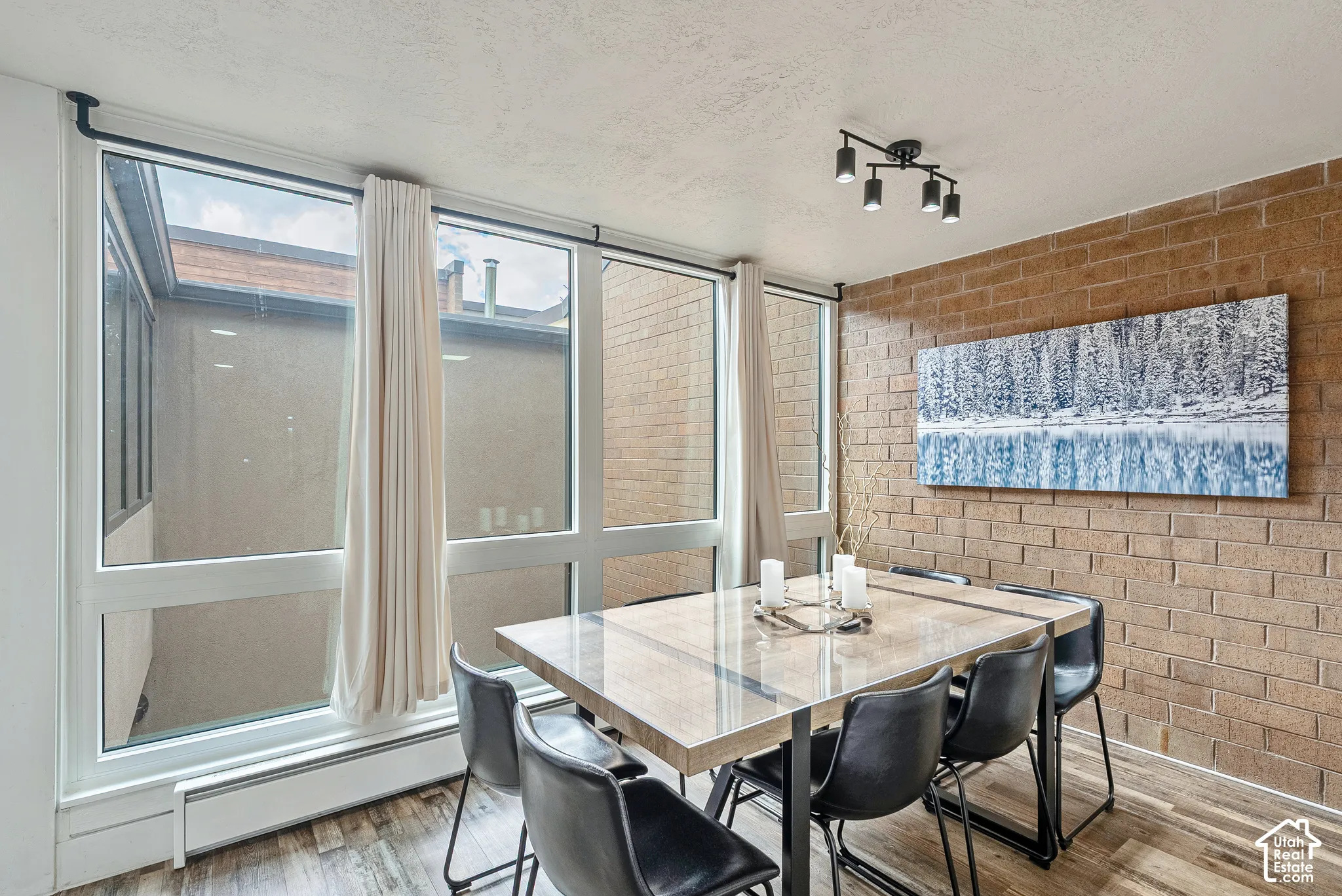 Dining area featuring an exposed brick accent wall and large windows