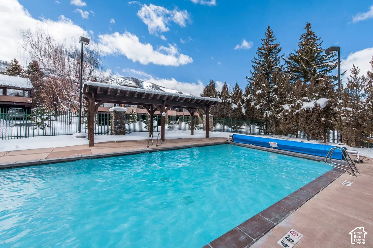 Outdoor swimming pool featuring a pergola, concrete decking, and metal fencing