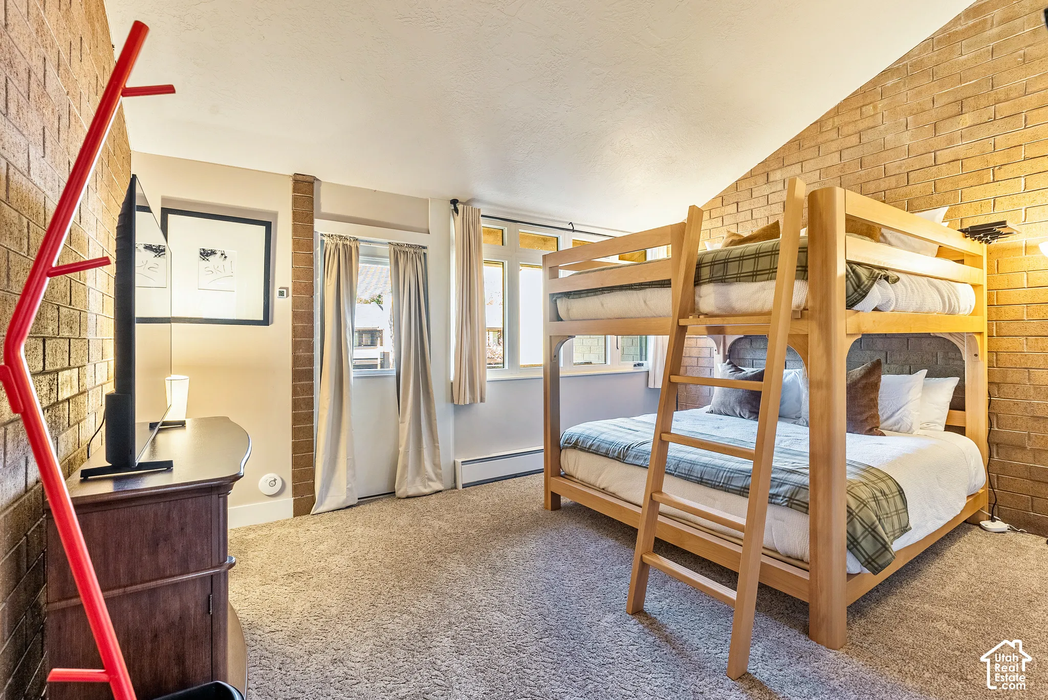 Accommodating room featuring a wooden bunk bed, light brown brick accent walls, and neutral-toned carpeting