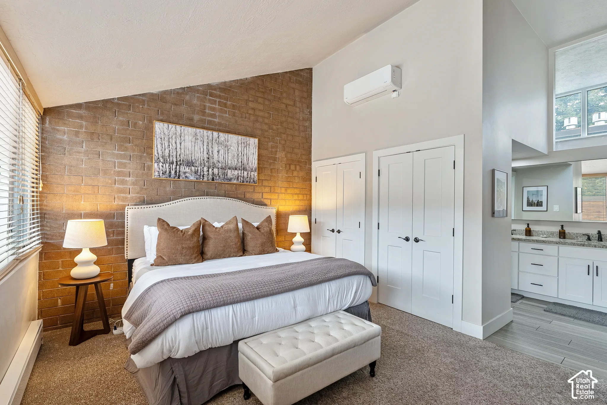 Bedroom area featuring a textured brick accent wall and light-colored carpeting