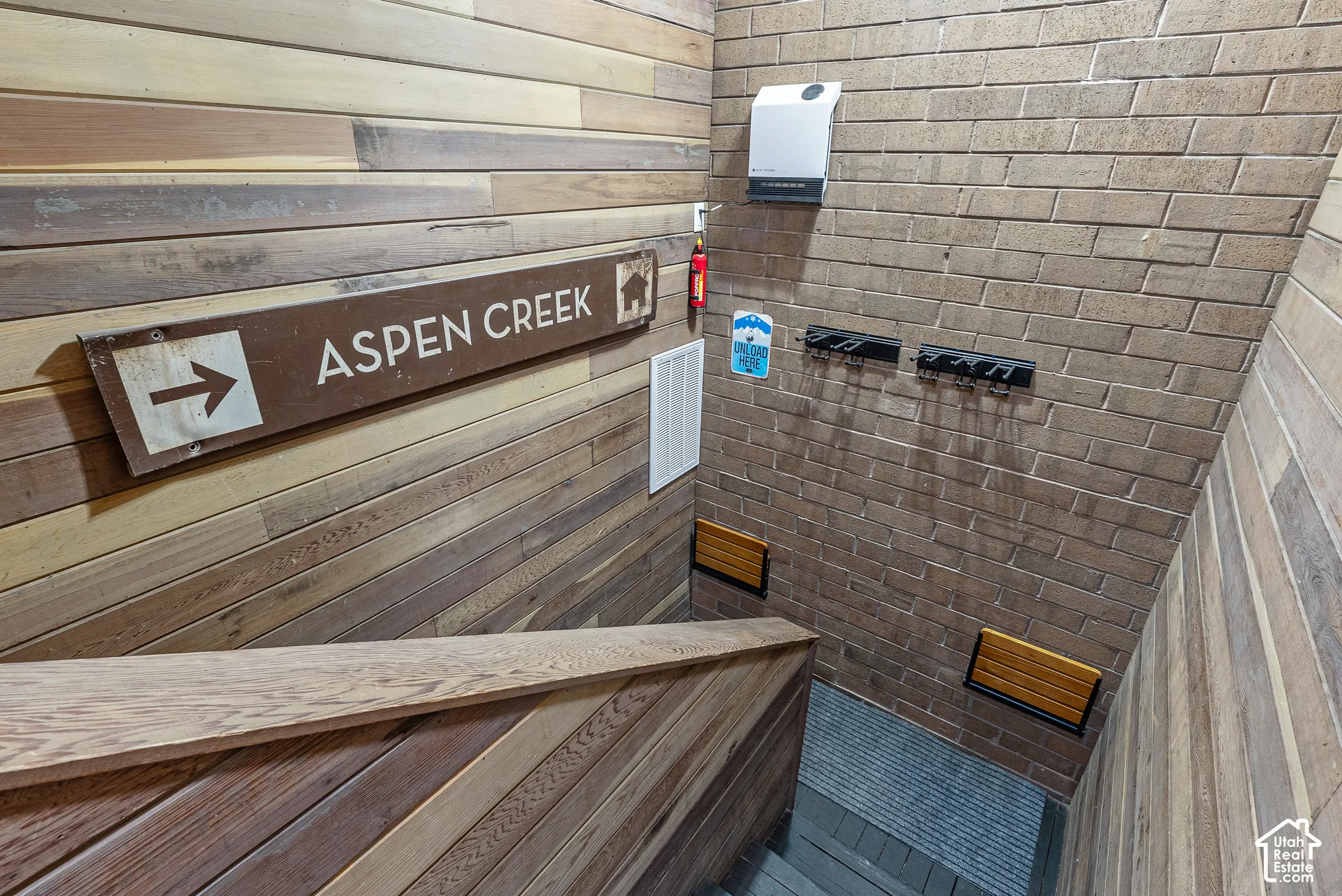 Stairwell featuring wood-finish wall paneling, brick-finish wall, and integrated wooden handrail