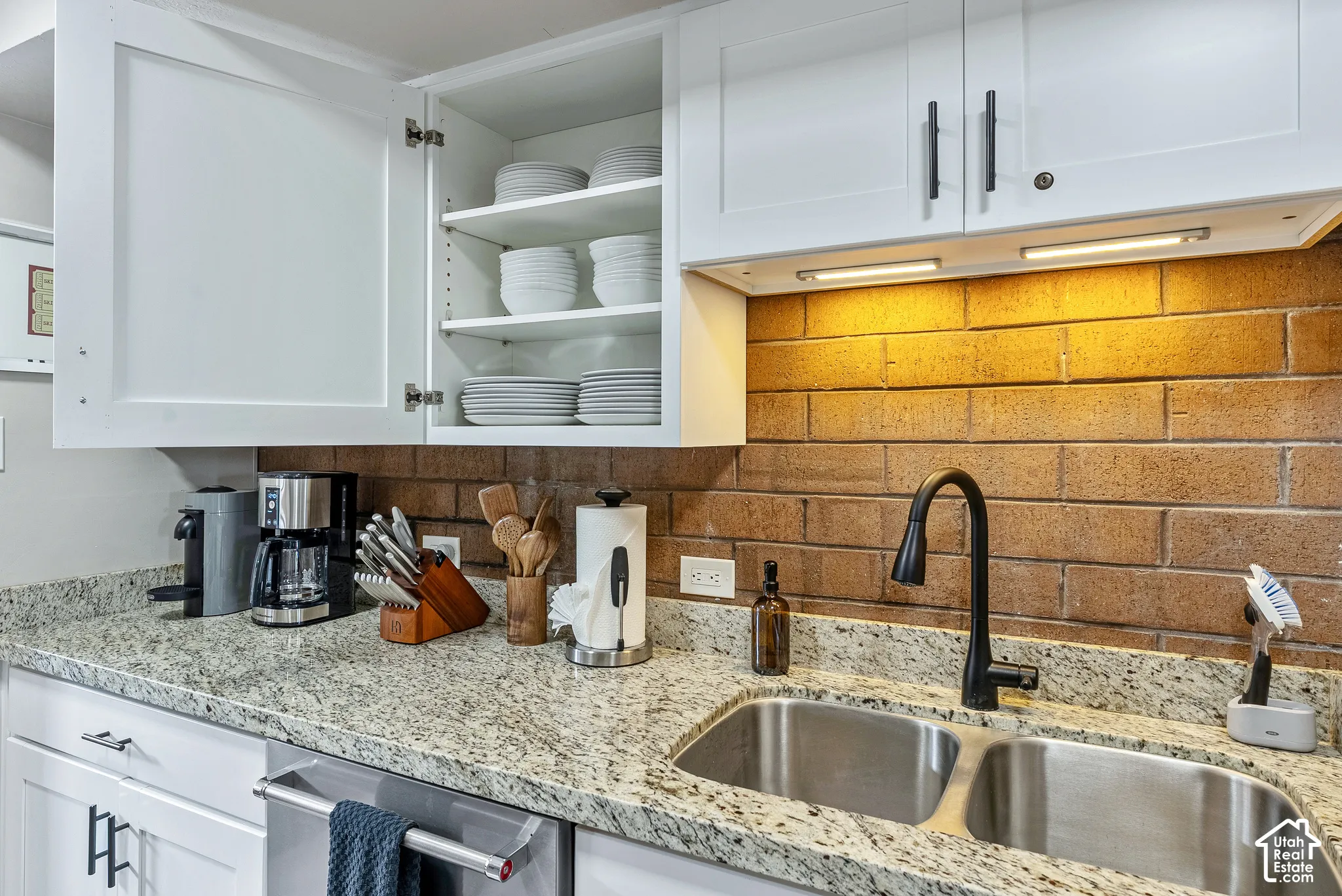 Kitchen featuring white shaker-style cabinetry, granite-finish countertops, and a brick-look backsplash