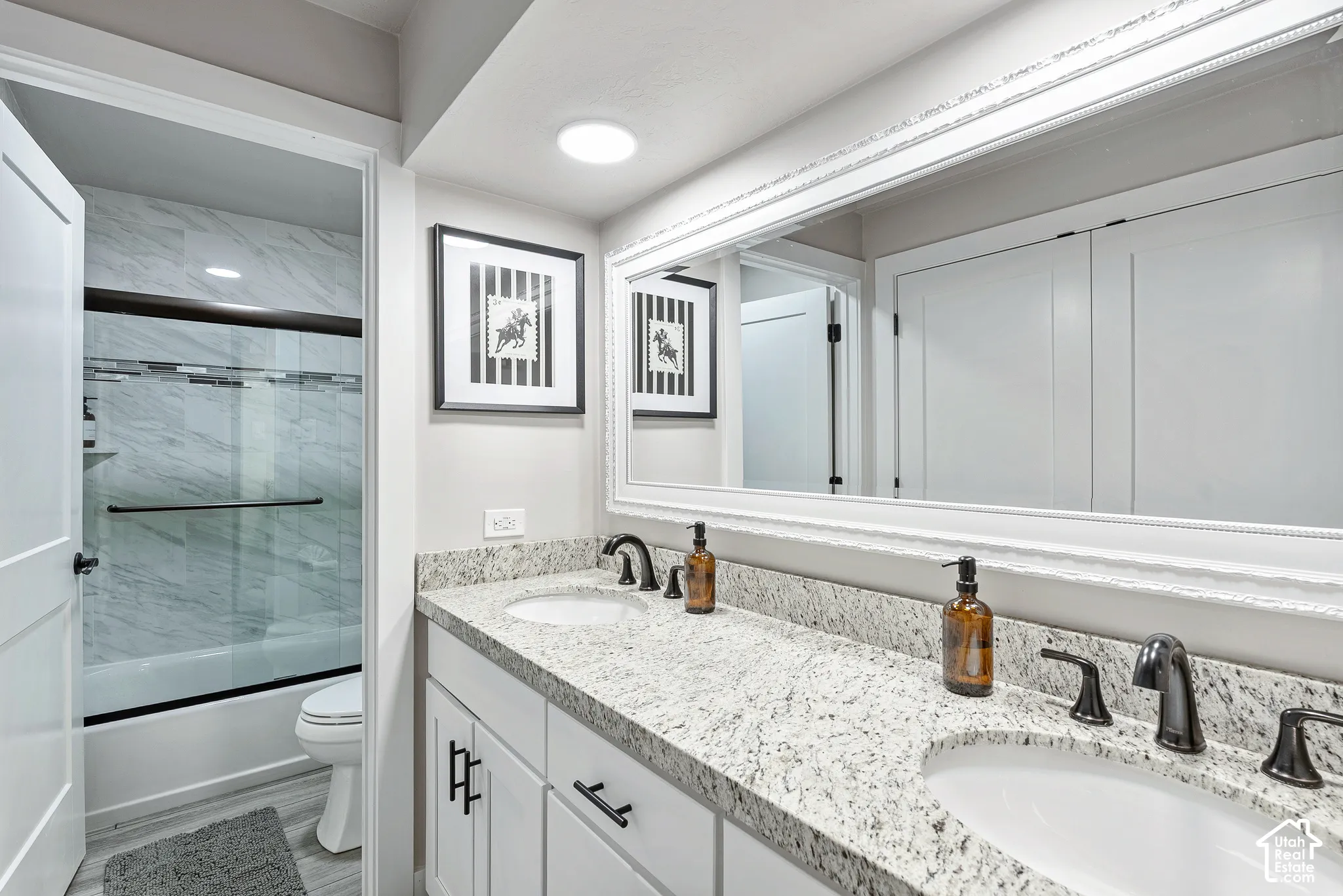 Bathroom featuring a double vanity with stone countertops, undermount sinks, and matte black hardware