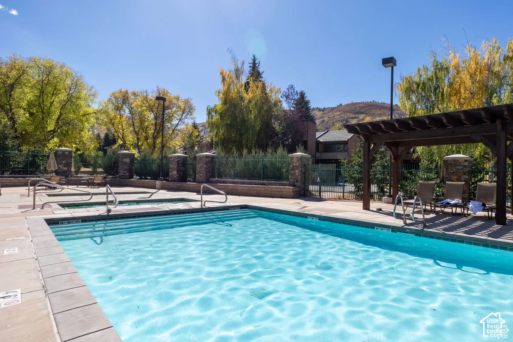 Outdoor swimming pool with integrated spa and surrounding stone-clad pillars