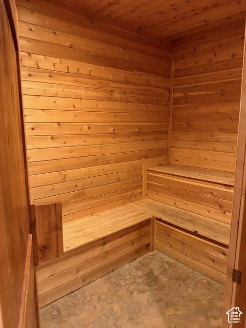 Sauna featuring tongue-and-groove wood paneling, multi-level built-in bench seating, and stone-finish flooring