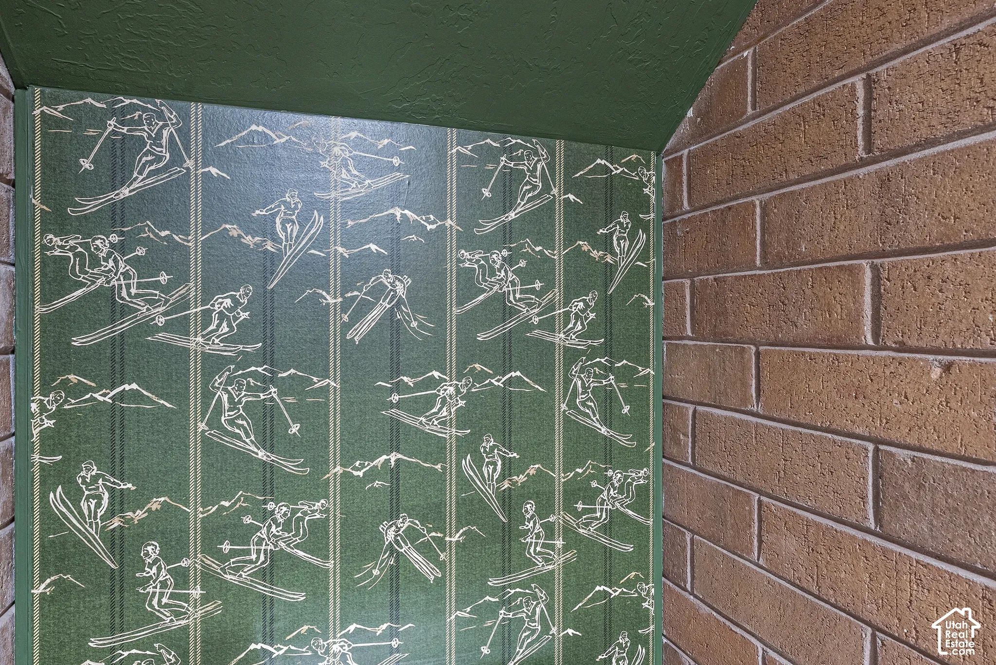 Textured brick wall complementing a green wallpaper with a ski-themed pattern