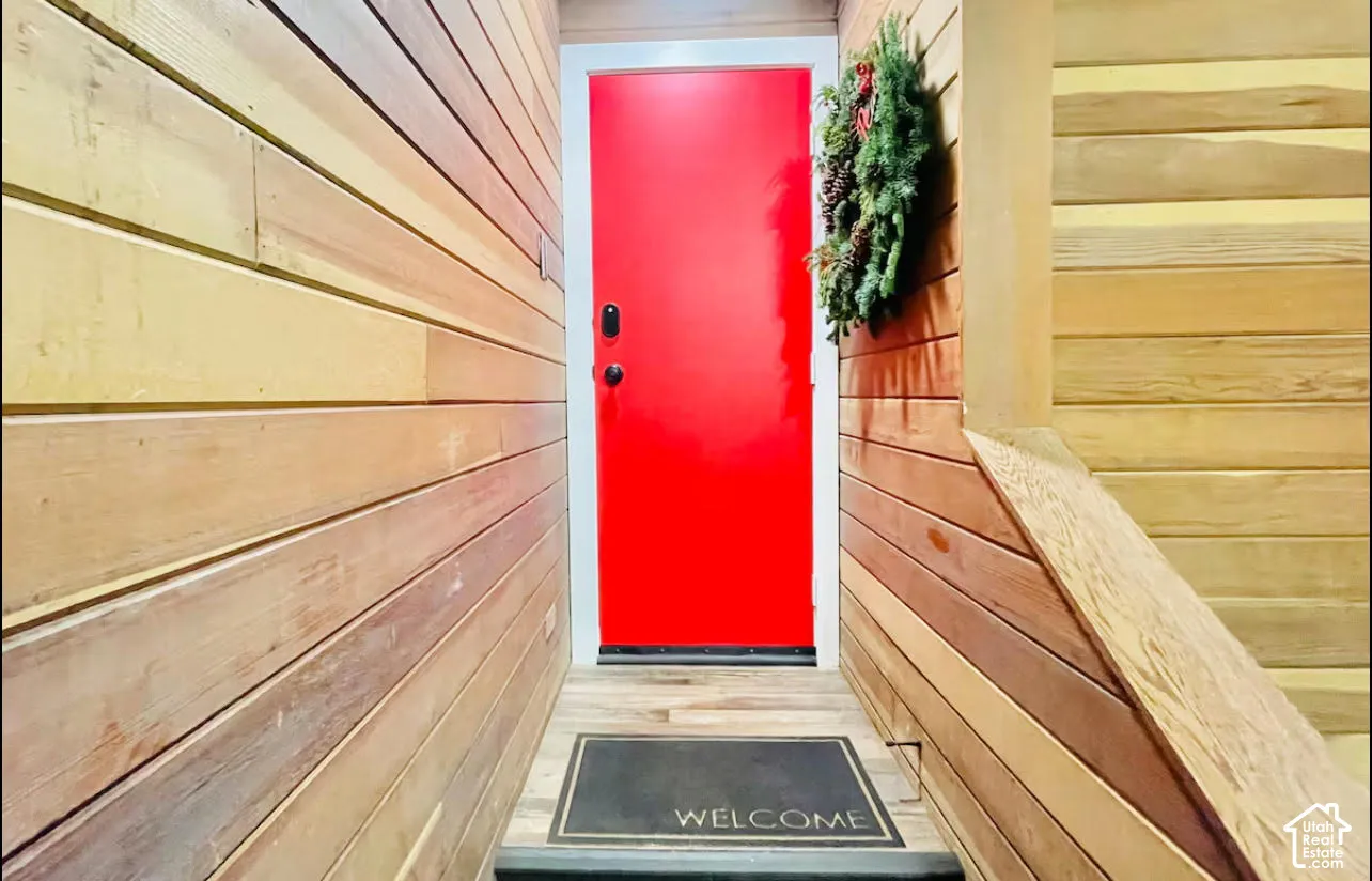 Vibrant red entry door framed by light wood-finish siding walls