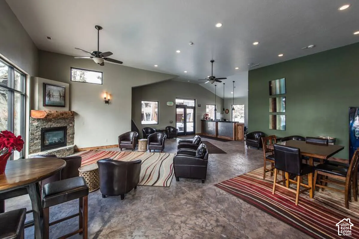 Spacious common area featuring a stone-clad fireplace with a wood mantel, vaulted ceilings, and recessed lighting