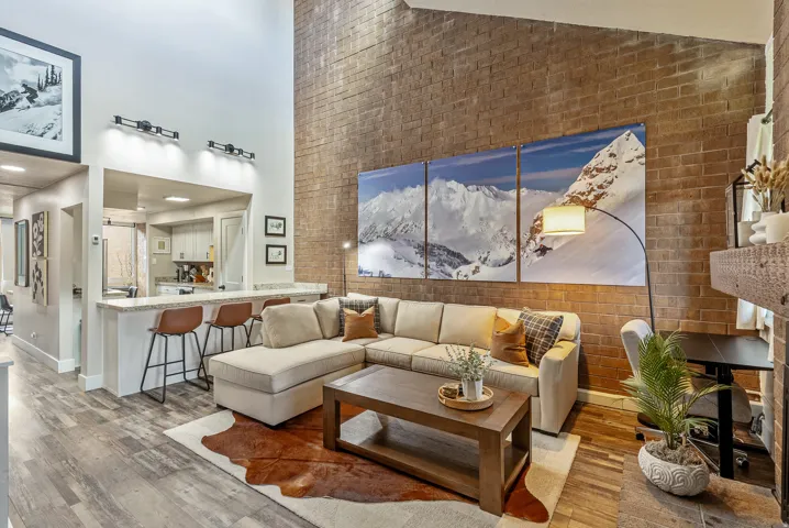 Living area with high vaulted ceilings and a floor-to-ceiling brick accent wall
