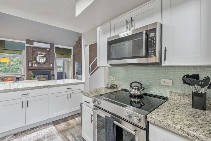 Modern kitchen featuring white cabinetry with dark hardware, granite countertops, and a subway tile backsplash
