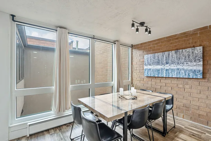 Dining area featuring an exposed brick accent wall and large windows