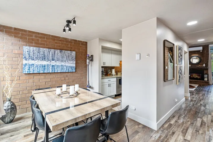 Dining area featuring a brick accent wall, wood-finish flooring, and recessed lighting