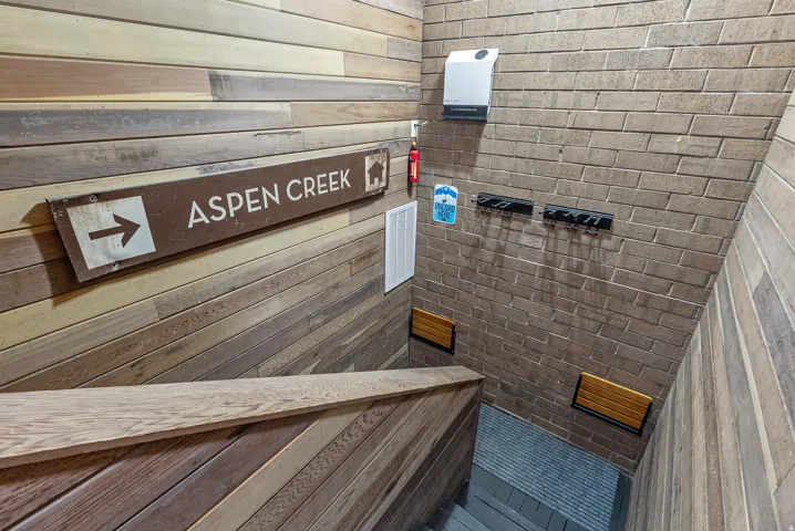 Stairwell featuring wood-finish wall paneling, brick-finish wall, and integrated wooden handrail