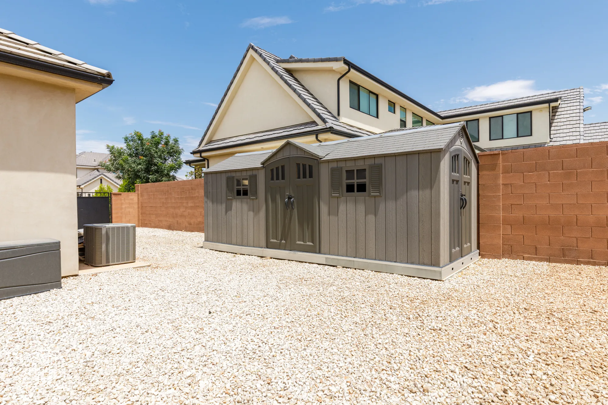 Expansive gravel yard featuring a multi-section shed with double doors and window details