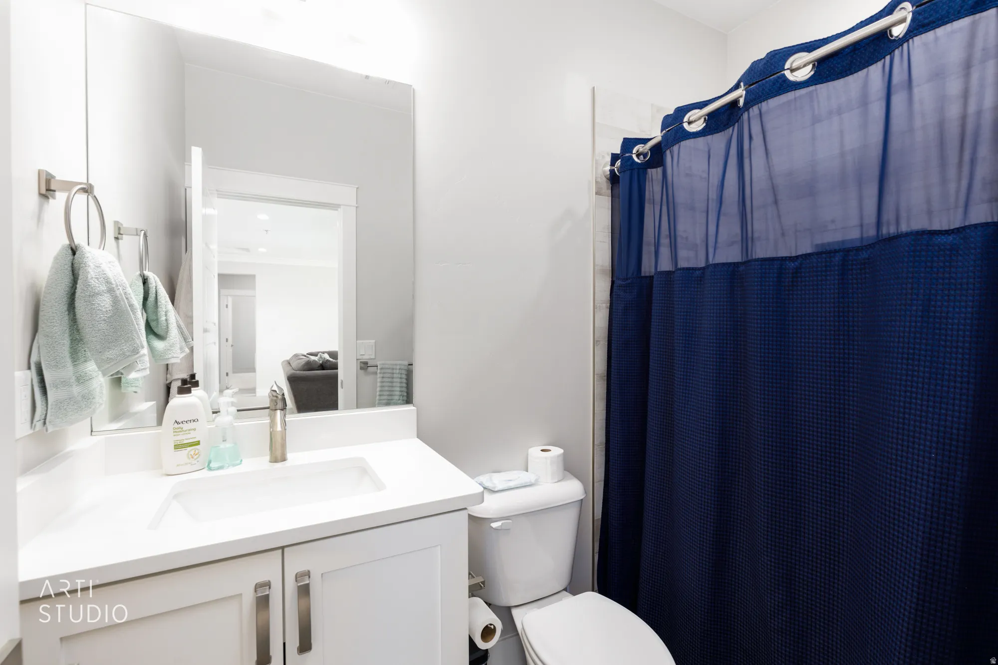 Bathroom featuring a white vanity with an integrated sink, brushed nickel faucet, large wall mirror, and a white toilet