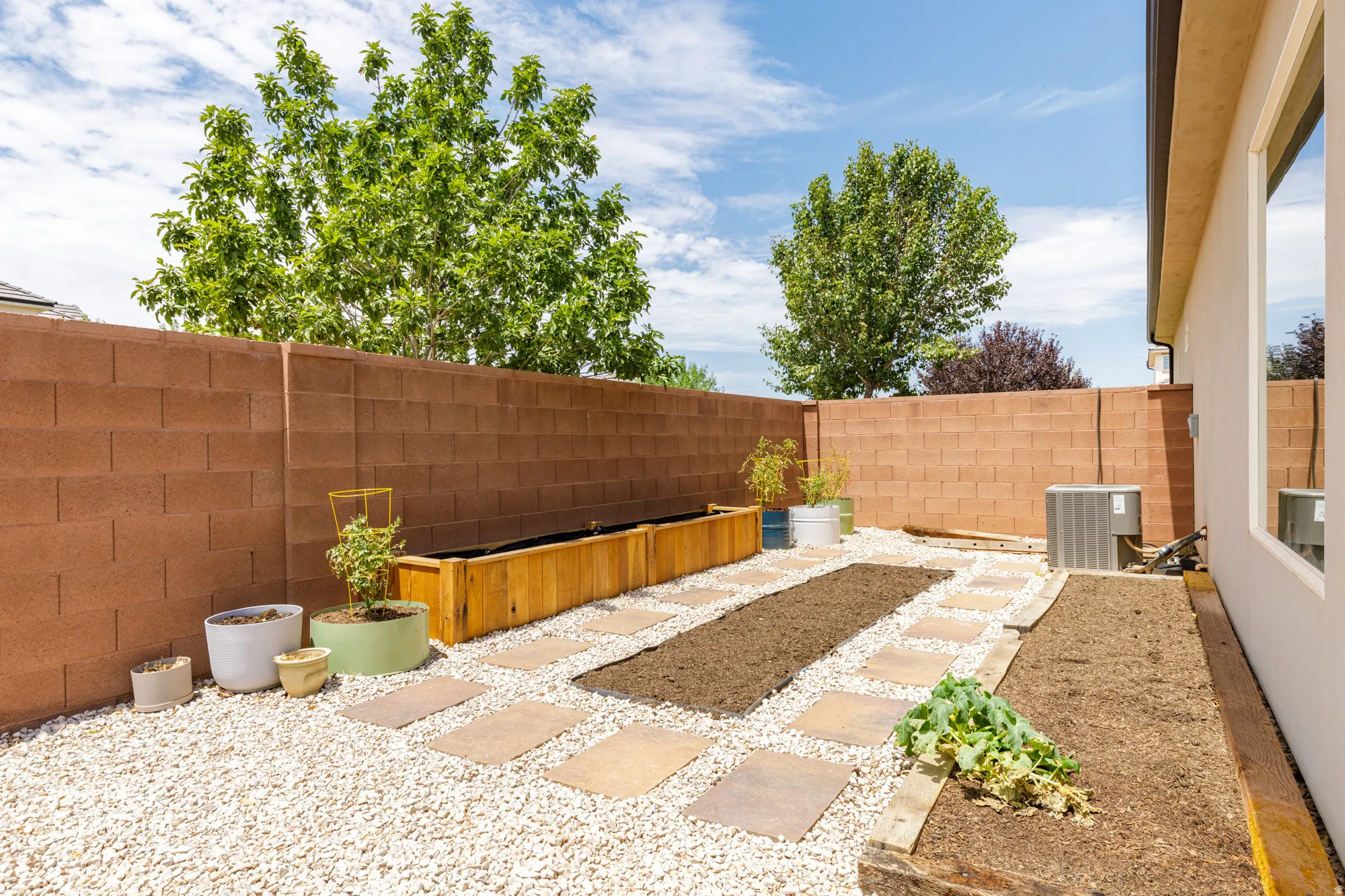 Backyard featuring a privacy block wall and a combination of pea gravel and stepping stones