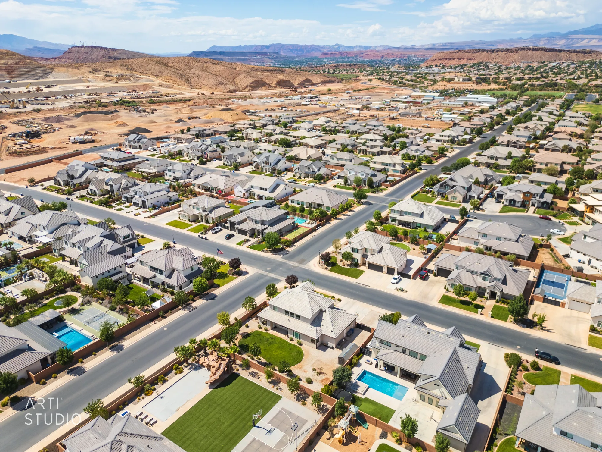 Expansive aerial perspective showcasing a residential neighborhood with numerous single-family homes and mountain scenery