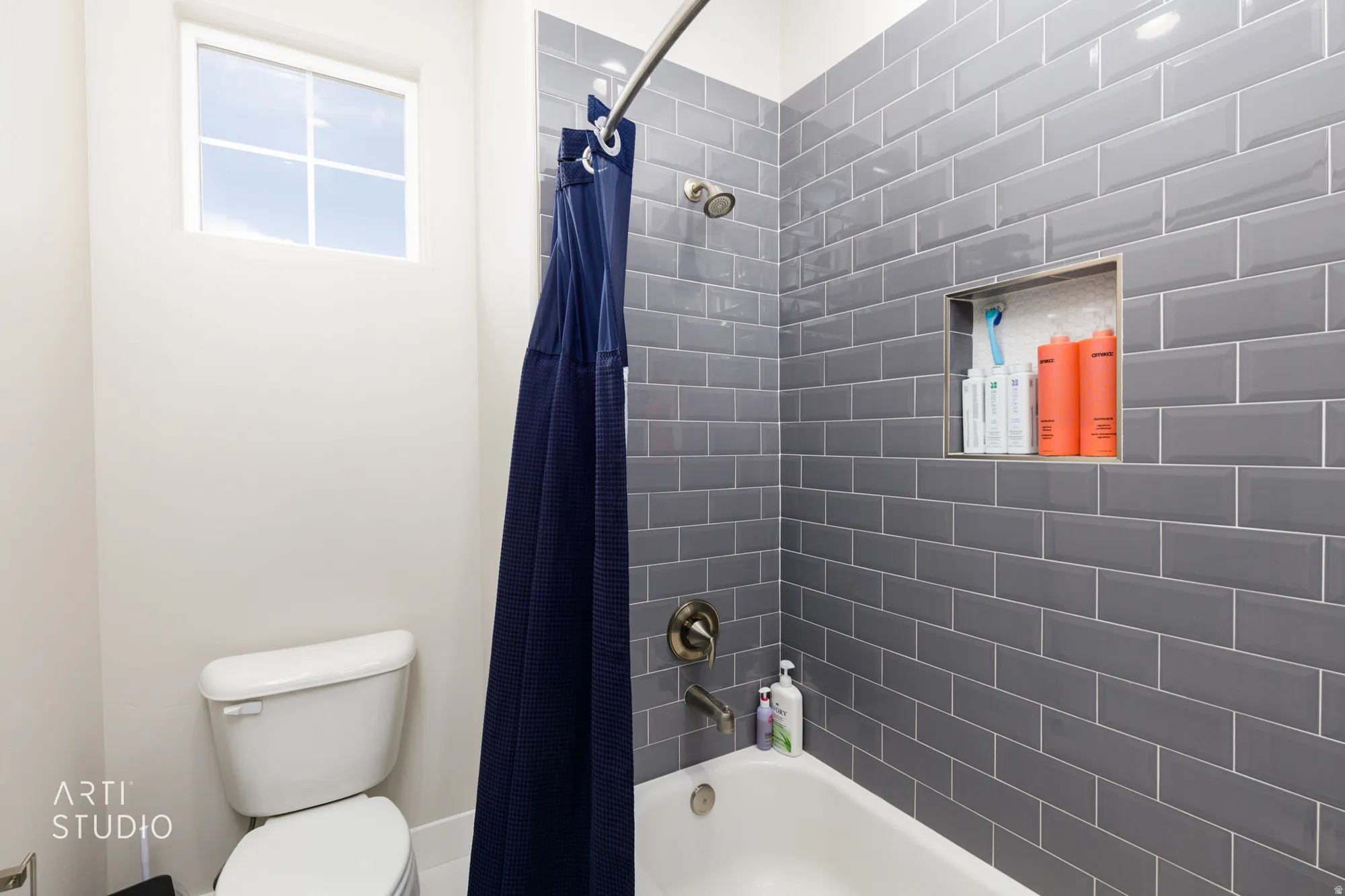Bathroom featuring a tub/shower combination with gray subway tile surround and a built-in shower niche