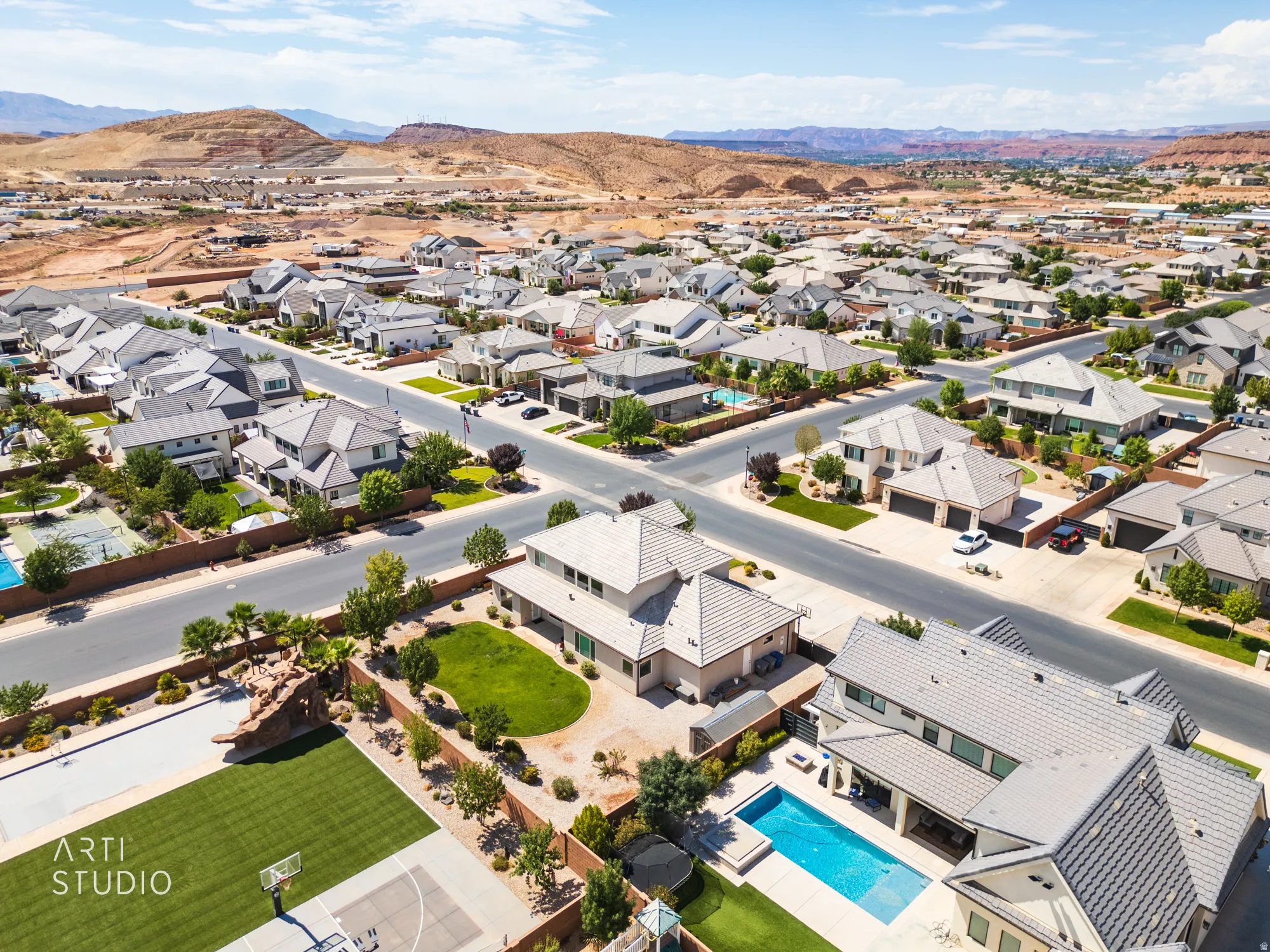 Expansive community featuring contemporary residential architecture, mature landscaping, paved roads, and clear skies