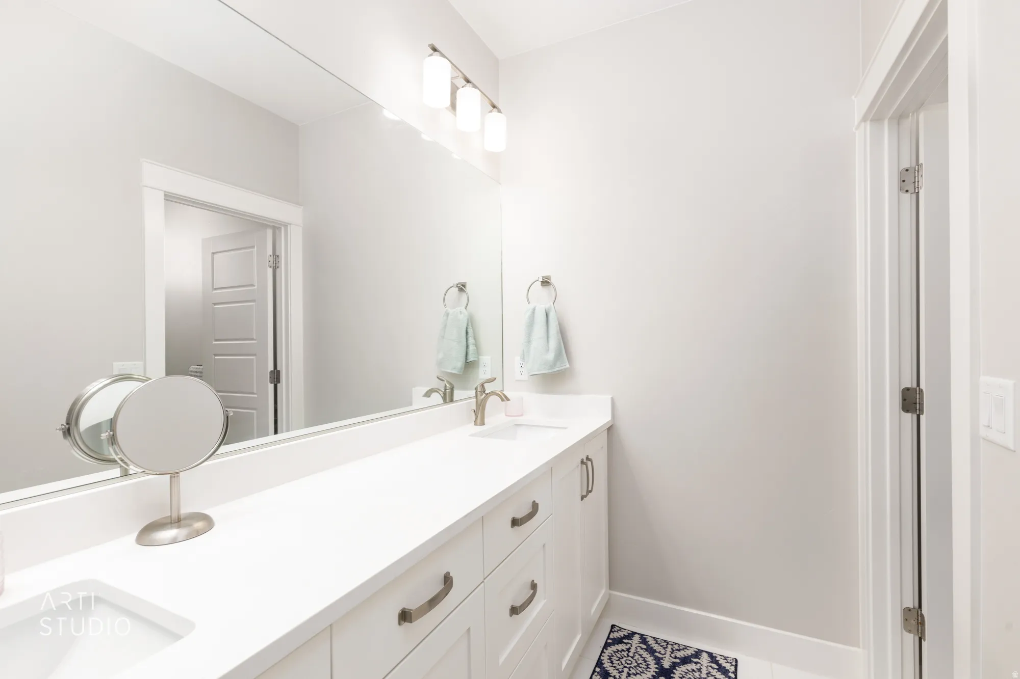 Double vanity with integrated sinks, white cabinetry, and brushed nickel hardware