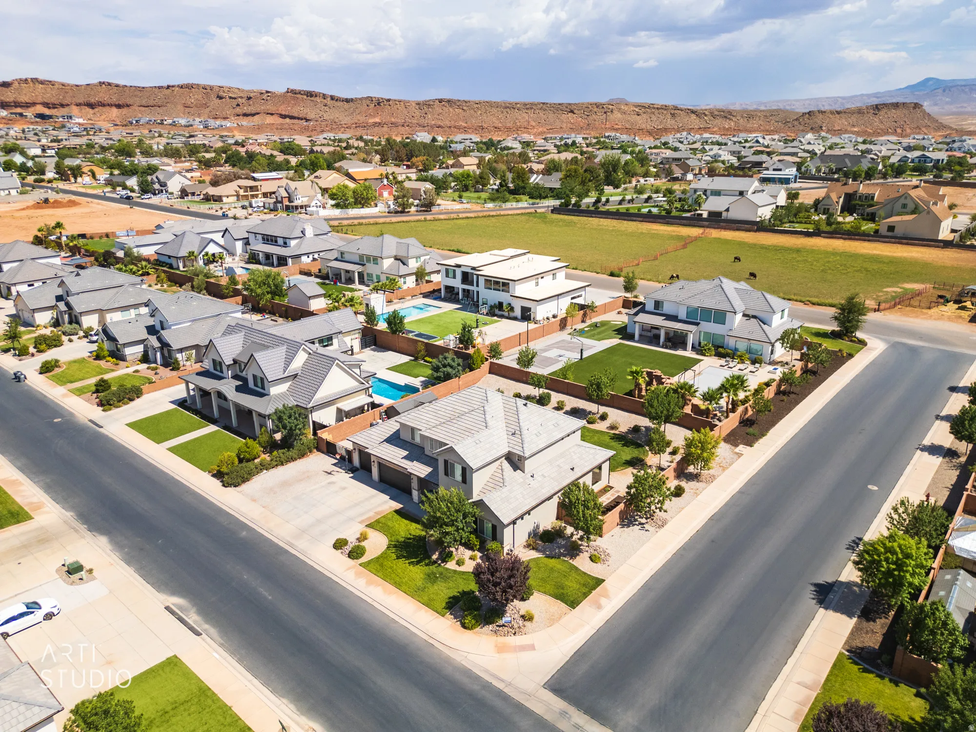 Expansive residential neighborhood with varied architectural styles, manicured landscaping, paved streets, and a mountainous backdrop