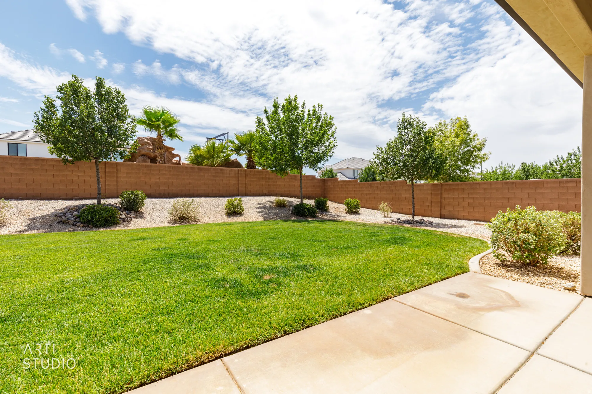 Expansive green lawn with a curved concrete patio and xeriscaped borders