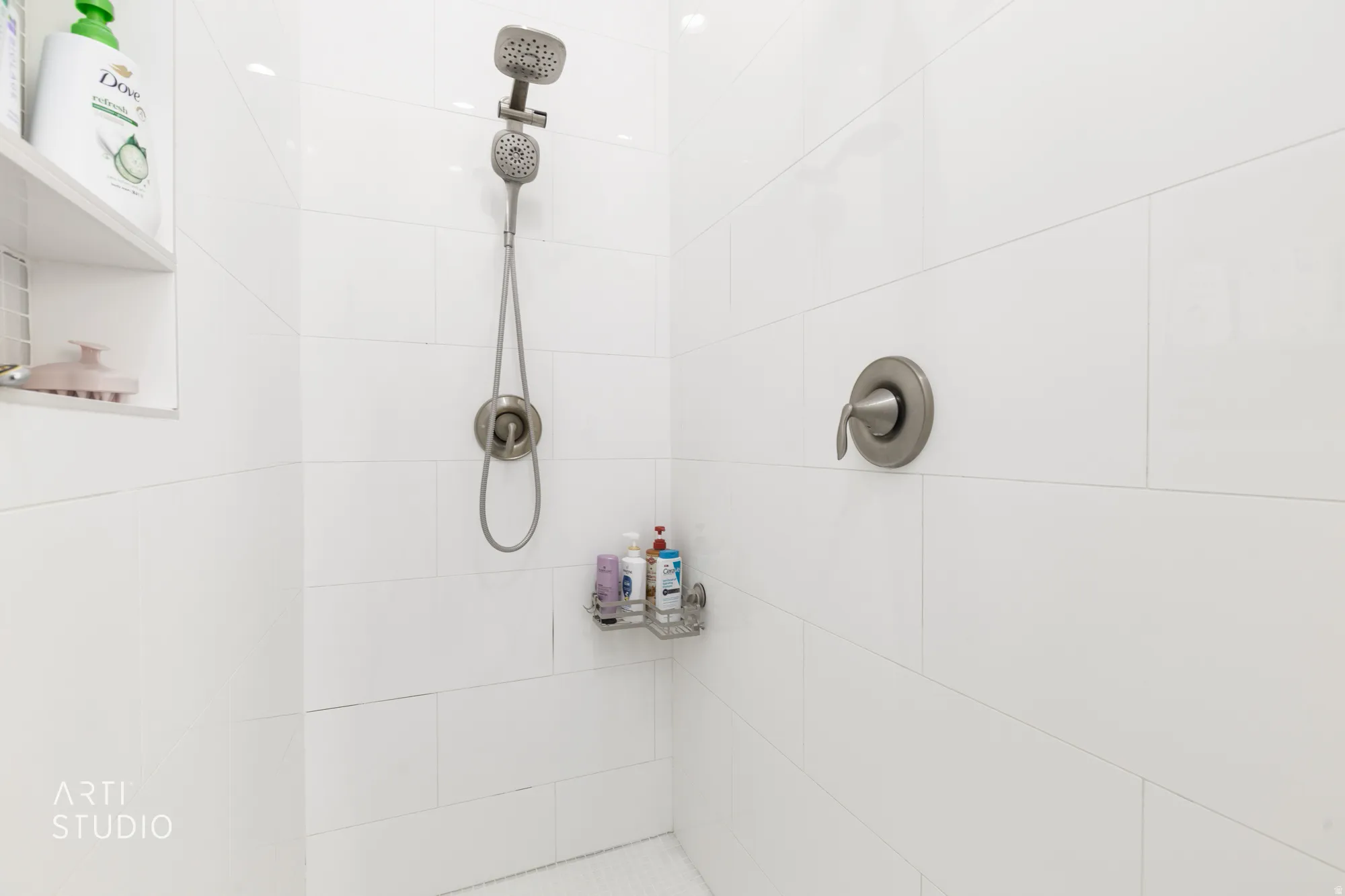 Shower enclosure with white subway tile, a recessed shower niche, and brushed nickel fixtures including a rainfall showerhead and handheld sprayer