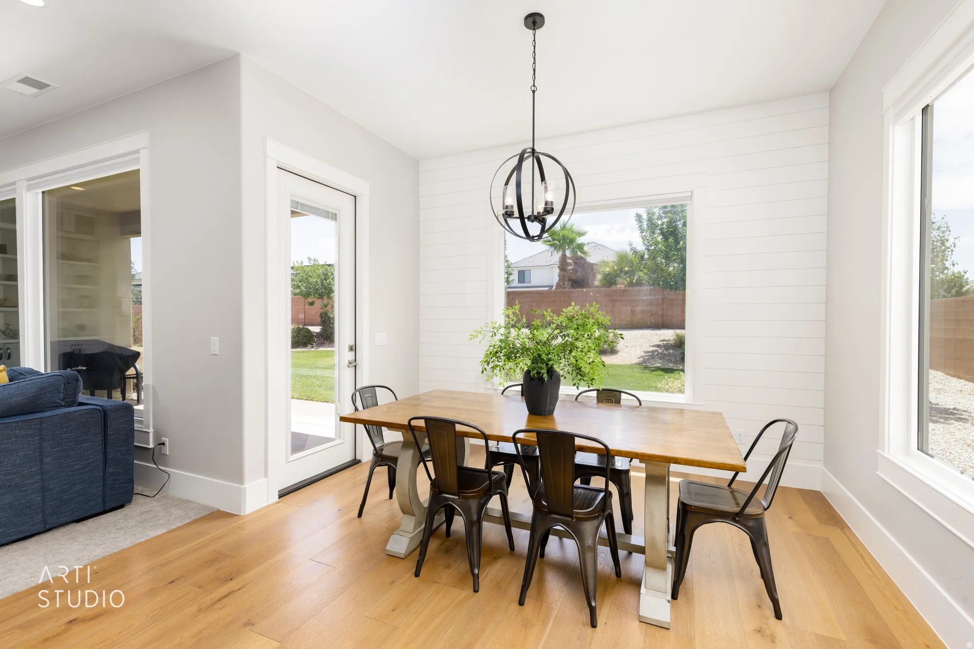 Dining area featuring wood-finish flooring, white shiplap accent wall, and a contemporary orb chandelier