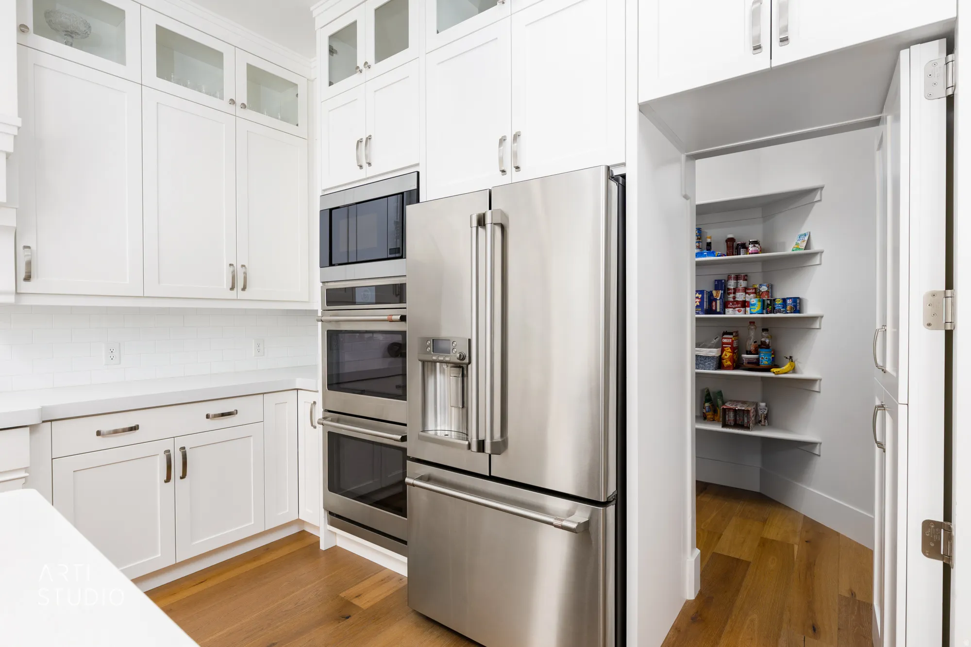 Stainless steel refrigerator and double wall ovens complement the white shaker cabinetry